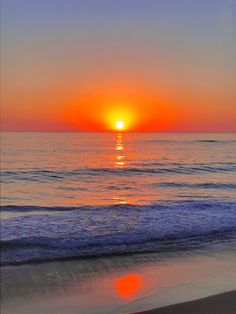 the sun is setting over the water at the beach