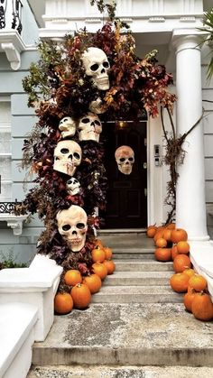 halloween decorations with skulls and pumpkins on the front steps in front of a house