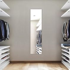 an empty walk in closet with white shelving and clothes hanging on the shelves,