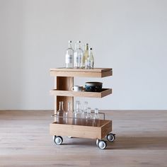 a wooden cart with wine glasses and bottles on it sitting on a hard wood floor