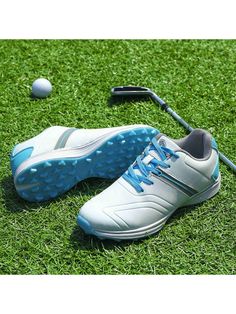 a pair of white and blue shoes sitting on top of a green field next to a golf ball