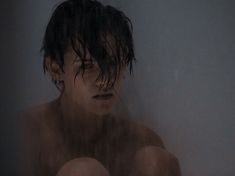 a man with wet hair sitting in the shower