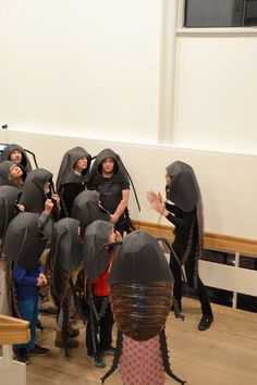 a group of people dressed in black and wearing hoods, standing around each other