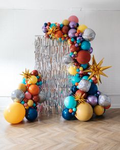 a christmas tree made out of balloons and confetti is displayed on the floor