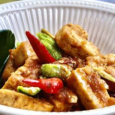 a white bowl filled with tofu and vegetables