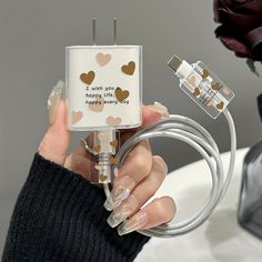 a woman is holding an electric charger with hearts on it and two plugs attached