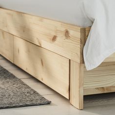 a wooden bed frame sitting on top of a tiled floor next to a white pillow