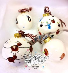 four white christmas balls with designs on them and one has a ribbon around its neck