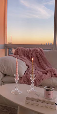 two candles are sitting on a coffee table in front of a window with a view