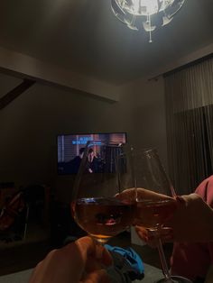 two people toasting wine glasses in front of a flat screen tv