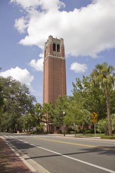 a tall tower with a clock on the side of it next to trees and bushes