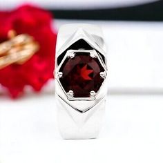 a close up of a ring with a red stone in the center on a white surface