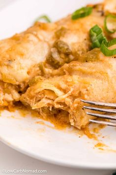 a white plate topped with lasagna covered in sauce and green peppers next to a fork