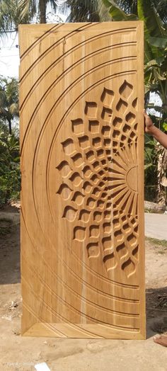 a man standing next to a carved wooden panel with an intricate design on it's side