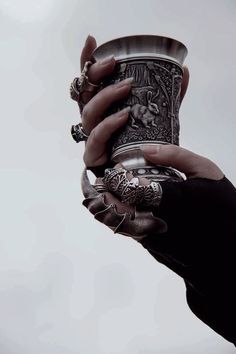 black and white photograph of a person's hand holding an ornately decorated cup