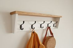 a coat rack with three coats hanging from it and two purses on the hooks