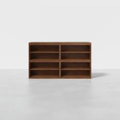 an empty wooden bookcase on a white surface with no people around it and one section missing