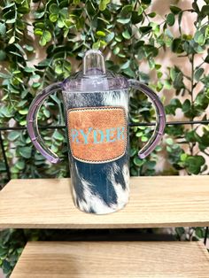 a blue and white cup with the word ryder on it sitting on a wooden table