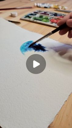 someone is painting on paper with a brush