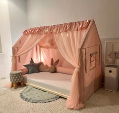 a child's bed with pink canopy and curtains