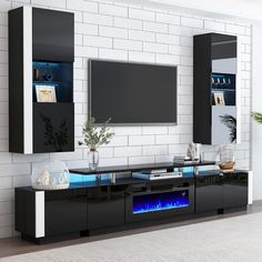 a modern entertainment center with blue flames in the fireplace and white brick wall behind it