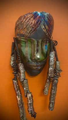 a mask with metal wires attached to it's face and two hands hanging from the side