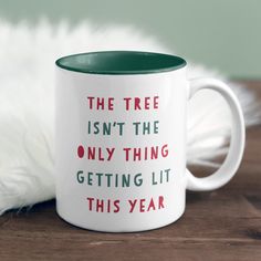 a green and white coffee mug with the words, the tree isn't the only thing getting lit this year