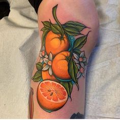 an orange with leaves and flowers on the thigh is shown in this tattoo artist's image