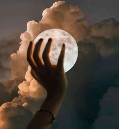 a person's hand reaching up to the moon