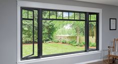 an empty living room with large windows looking out onto the yard and trees in the backyard