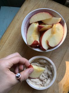 a person is holding an apple slice in front of a bowl of oatmeal