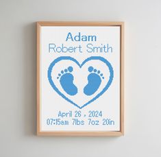 a cross stitch baby's birth announcement with footprints in the shape of a heart