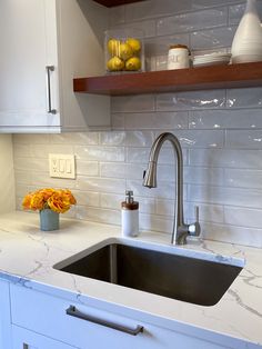 The subway tile backsplash adds texture and interest with a wavy, delicately textured surface, and a hint of color to provide a perfect backdrop for the white cabinets and maple floating shelves. Simple Grey Backsplash, Backsplash For White Cabinets Subway Tile, Backsplash For White Marble Countertops, White Textured Subway Tile Bathroom, White Tile Backsplash With White Cabinets, Wavy Tile Backsplash Kitchen, Wavy Kitchen Backsplash, Uneven Subway Tile Backsplash, White Wave Tile Kitchen Backsplash