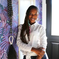 a woman with dreadlocks standing next to a wall