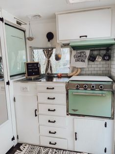 an old fashioned kitchen with white cabinets and green stove top oven in the middle of it