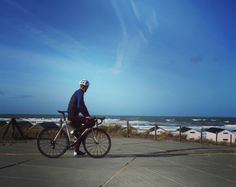 a man riding a bike on top of a parking lot next to the ocean