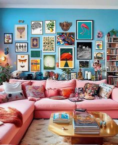 a living room filled with pink couches and lots of pictures on the wall above them