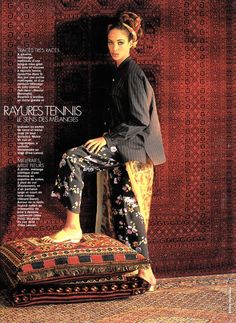 a woman sitting on top of a cushion in front of a rug