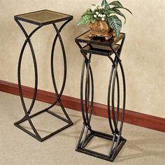 two metal plant stands sitting next to each other on the floor in front of a wall