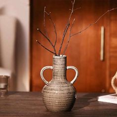 a vase with branches in it sitting on a table next to a teddy bear and other items