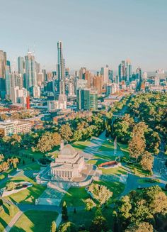 an aerial view of a city with tall buildings and green trees in the foreground