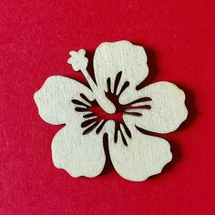 a white flower with black centers on a red background, cut out from plywood