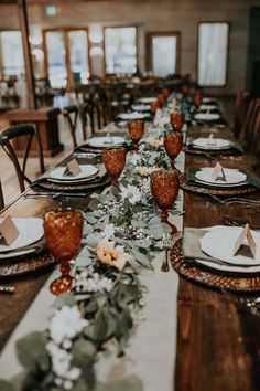 a long table set with place settings and flowers