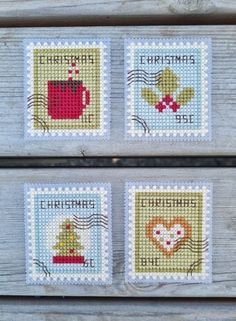 four cross stitch christmas coasters on a wooden surface