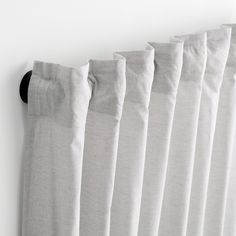 white curtains hanging on the wall in front of a window with a black curtain rod