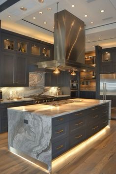 a large kitchen with marble counter tops and stainless steel appliances, along with wooden flooring