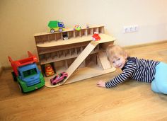 a toddler plays with toys on the floor in front of a toy train set