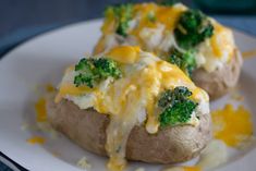 two stuffed potatoes with broccoli and cheese on them sitting on a white plate