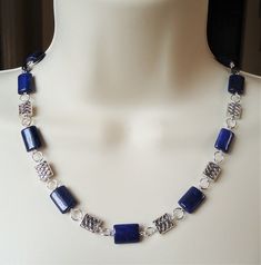 "This necklace combines beautiful blue lapis lazuli natural stone, with sculpted metal castings. Metal is made of pewter and plated in sterling silver. Necklace is finished with a simple lobster claw closure. Necklace measures 18\" in length, with 2 inches extension. This gorgeous necklace is unique, feminine and eye-catching, Perfect for anyone that wants to make a statement or to wear to a special occasion!" Handmade Silver Sodalite Necklaces, Handmade Silver Sodalite Necklace, Handmade Royal Blue Lapis Lazuli Jewelry, Silver Lapis Lazuli Jewelry With Polished Beads, Silver Beaded Lapis Lazuli Jewelry, Silver Lapis Lazuli Beaded Necklace, Lapis Lazuli Jewelry With Silver Beads For Gifts, Lapis Lazuli Gemstone Beads Necklace In Silver, Silver Lapis Lazuli Necklace With Polished Beads