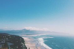 an ocean view from the top of a hill with houses on it and mountains in the distance